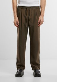 Pantalons avec cordon de serrage de couleur vert olive, à coupe décontractée, fabriqués à partir d'un tissu lisse. Comprend une taille élastique et des jambes fuselées.