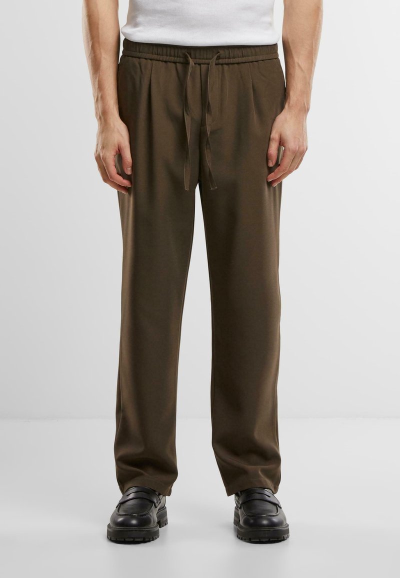 Pantalons avec cordon de serrage de couleur vert olive, à coupe décontractée, fabriqués à partir d'un tissu lisse. Comprend une taille élastique et des jambes fuselées.