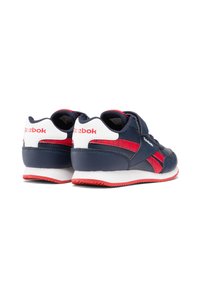 Zapatillas deportivas azul marino con acentos rojos, parte superior sintética texturizada, costuras blancas y una suela de goma con un diseño de banda de rodadura en patrón.