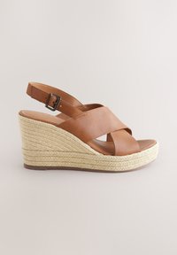 Sandale compensée en cuir marron avec des lanières croisées, dotée d'une plateforme en jute tissé. Bride de cheville ajustable avec boucle en métal.