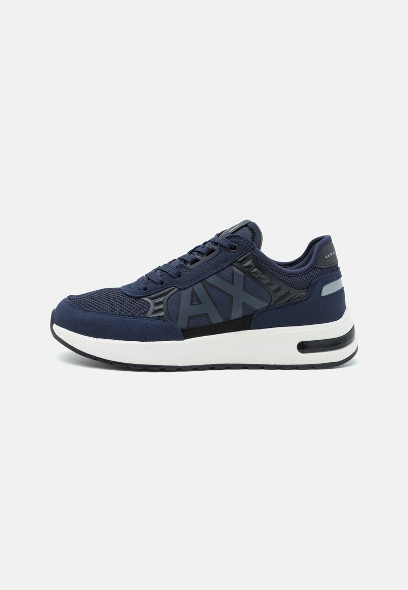 Baskets bleu marine avec détails en mesh et en daim, logo noir "AX" sur le côté, semelle blanche et bande réfléchissante au talon.