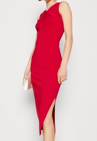 Červené přiléhavé šaty s jedním ramenem, ke kolenům s bočním rozparkem. Vyrobeno z hladké látky, s čistým, minimalistickým vzhledem.