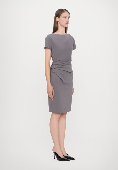 Grey fitted dress with short sleeves, gathered side detailing, and a knee-length hem. Accompanied by black high-heeled shoes.