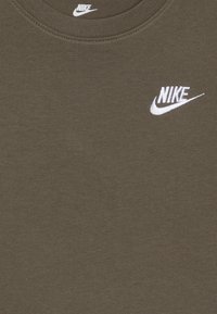 Olivno zelena bombažna majica s kratkimi rokavi in krožnim izrezom, ki ima na prsih belo vezeno Nike logo. Mehka, gladka tekstura.