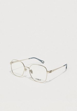 Lunettes carrées avec une fine monture en métal doré, des verres transparents et une branche accentuée de bleu. Présente des détails de logo sur la monture.