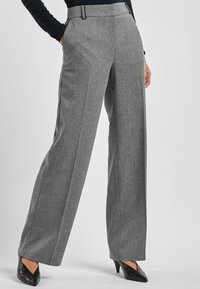 Grijze geruite wijde broek met een zachte textuur, getailleerde pasvorm, zijzakken en een hoge tailleband. Gepaard met zwarte hakken.