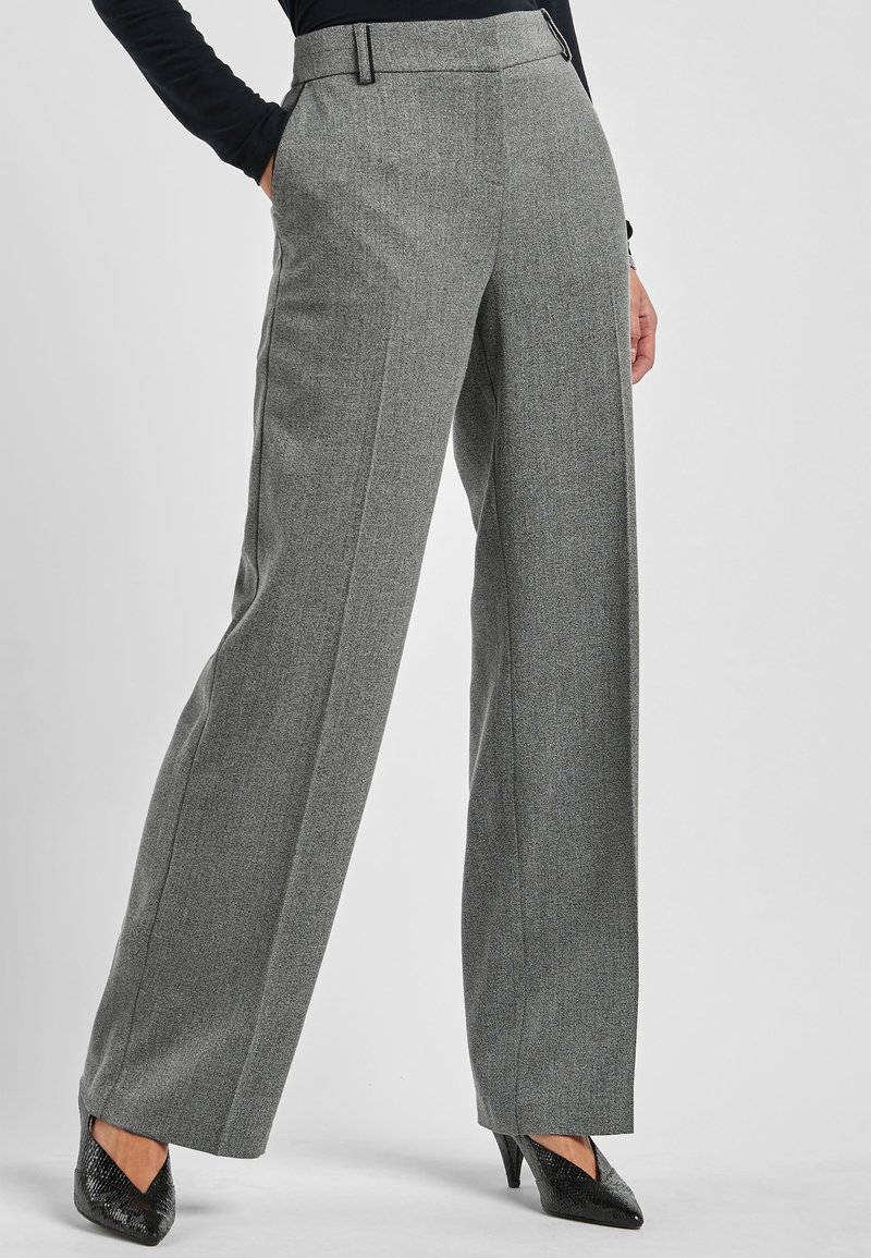 Grijze geruite wijde broek met een zachte textuur, getailleerde pasvorm, zijzakken en een hoge tailleband. Gepaard met zwarte hakken.