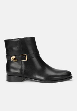Stivale alla caviglia in pelle nera con zip laterale, presenta una fascia con fibbia dorata e un accento con logo, tacco piatto e superficie liscia.