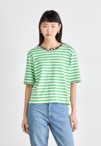 Groen en wit gestreepte T-shirt met een panterprint ronde hals, korte mouwen en een ontspannen pasvorm, gecombineerd met lichtblauwe denim jeans.