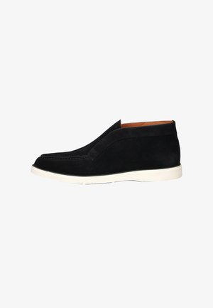 Black suede slip-on shoes with a white rubber sole, featuring a smooth texture and minimalistic design, no visible hardware or patterns.