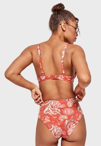 Top de bikini con estampado paisley rojo y parte inferior de cintura alta, con tirantes y un cierre en la parte trasera, de textura lisa y con patrón.