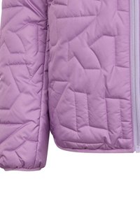 Tissu de veste matelassée violet avec des motifs de couture géométriques et une fermeture éclair visible à l'avant sur le côté droit.