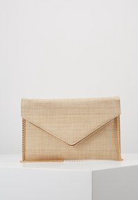 Pochette intrecciata beige con patta triangolare, tracolla a catena dorata e texture sottile, caratterizzata da un design minimalista senza elementi metallici visibili.