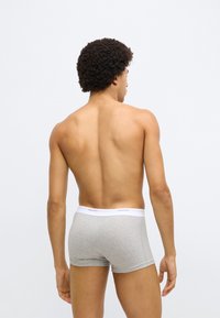 Boxer en coton gris avec une ceinture blanche, arborant le logo "GANT". Le design est ajusté et la texture est lisse.