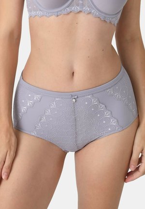 Frau trägt passenden grauen Spitzen-BH und hoch taillierte Slips mit kreisförmigen Spitzenmustern und kleinem Herzanhänger in der Mitte.