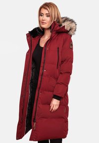 Red padded long coat with a fur-lined hood, front zip, and snap closures. Features side pockets and contrasting black cuffs.