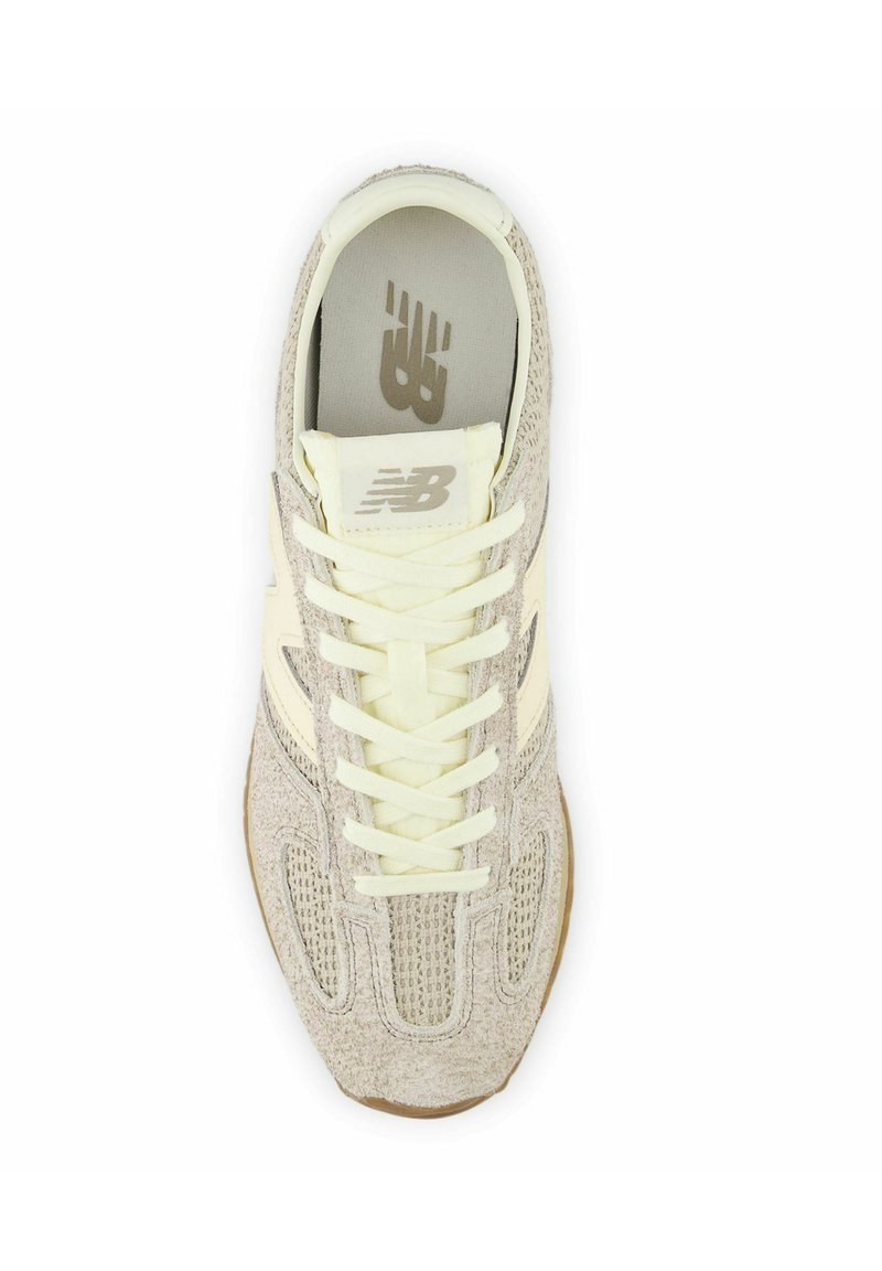 Light beige athletic shoe with a mesh and suede upper, textured design, cream laces, and a gum rubber outsole. Features a logo on the tongue.