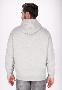 Grå hooded sweatshirt med en mjuk textur, med en avslappnad passform och ribbad mudd och nederkant, sedd bakifrån.