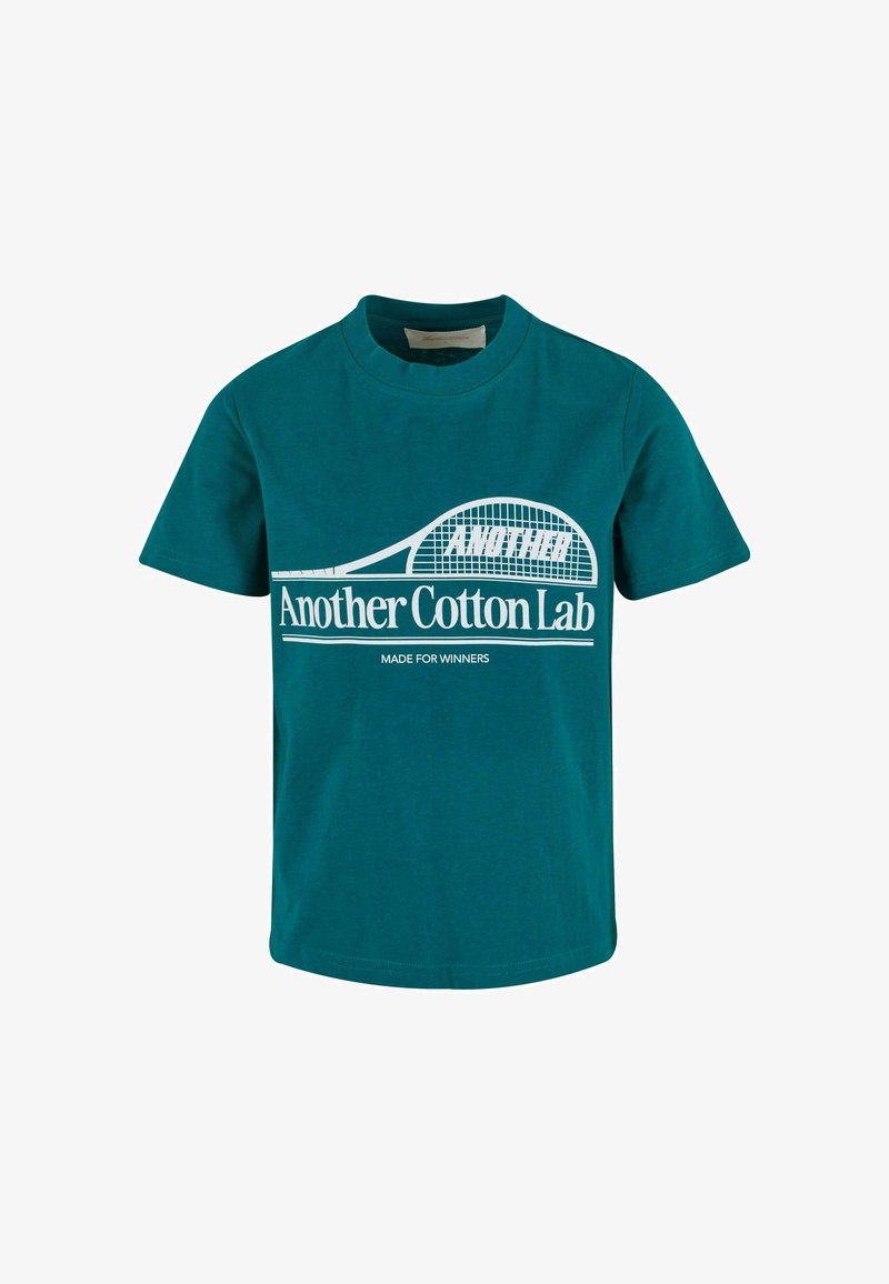 Mėlynos žalios spalvos medvilninė marškinė su trumpomisrankovėmis, apvalia iškirpte ir balta tekstu. Papuošta teniso raketės dizainu ir fraze "Sukurta nugalėtojams."