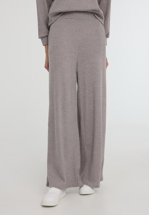 Pantaloni grigi a gamba larga realizzati in tessuto di maglia a costine, con cintura elastica e texture morbida, abbinati a sneakers bianche.