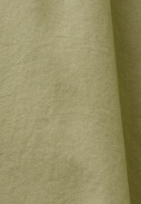 Tissu vert clair avec une texture lisse, tissée serrée et des plis doux.