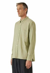 Camicia a maniche lunghe verde chiaro con colletto abbottonato, taschino sul petto e texture liscia. Progettata con una vestibilità comoda e orlo dritto.