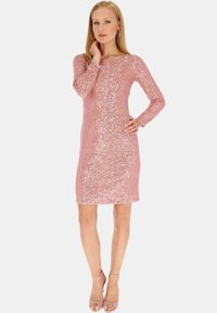 Różowa cekinowa sukienka z długimi rękawami i okrągłym dekoltem, dopasowana sylwetka, gładka tekstura, długość do kolan, zestawiona z beżowymi szpilkami.