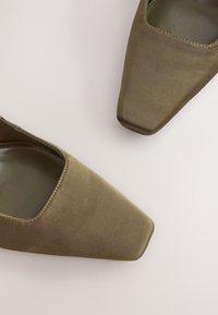 Oliivirohelised kõrged kontsaga kingad satiinise viimistlusega, ruudukujulise nina ja avatava küljeosaga, mis paljastab sileda sisevoodri.