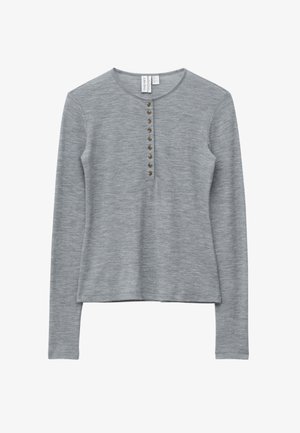 Vaaleanharmaa pitkähiha neulepaita, jossa pyöreä pääntie ja pystysuora rivi kahdeksaa pientä ruskeaa nappia edessä.