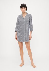 Randig kort pyjamaströja i marinblått och vitt, med krage, framknappar och uppvikt ärm. Mjukt material ger bekväm användning.