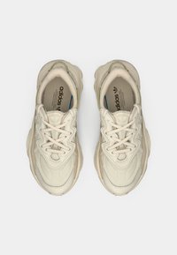 Sneakers Adidas in off-white con tomaia in tessuto texture, punta rotonda e design con lacci. Caratterizzati da un logo discreto e suola in gomma chunky.