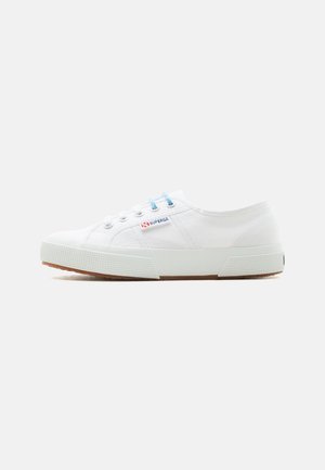 Hvid lavt snørresko i lærred med gummisål, blå og hvide snørebånd og mærket "Superga" på siden.