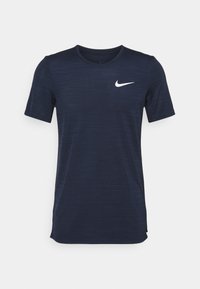Marinblå kortärmad sportt-shirt i texturerat tyg, med en vit Nike swoosh-logga på övre vänster sida.