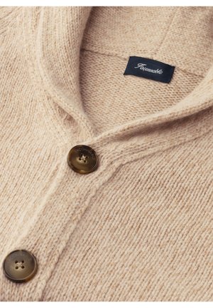 Beige Wolldenim mit Schalkragen, zwei braunen Knöpfen und einem gewebten Muster. Etikett auf der Innenseite in der Nähe des Kragens angenäht.