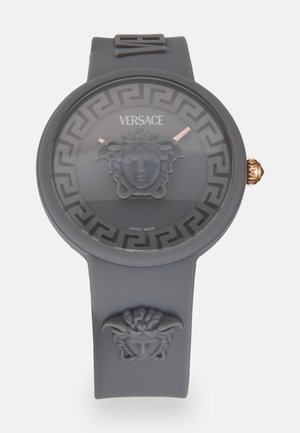 Versace ura z rjavim silikonskim paščkom, okroglo matirano številčnico s simbolom Meduze, vzorcem grškega ključa in poudarki iz rožnatega zlata. Švica izdelana.
