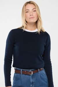 Navyfarbener, gerippter Langarmoberteil mit Rundhalsausschnitt, über einem weißen Rundhals-T-Shirt getragen, kombiniert mit hochgeschnittenen hellblauen Jeans und einem braunen Gürtel.