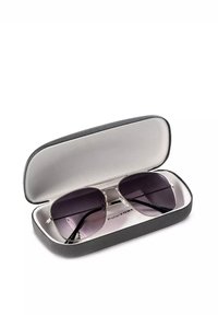 Okulary przeciwsłoneczne z gradientowymi, ciemnymi soczewkami w srebrnej metalowej oprawie, umieszczone w cienkim, czarnym, teksturowanym etui z miękkim, szarym wnętrzem.