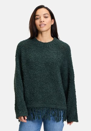 Pull vert foncé en matière texturée et pelucheuse. Présente un col rond et des détails à franges sur l'ourlet. Manches longues.