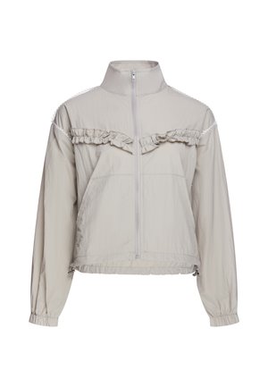 Giacca beige chiaro a maniche lunghe con cerniera frontale, collo alto, polsini e orlo elastici e dettaglio con volant su petto e spalle.