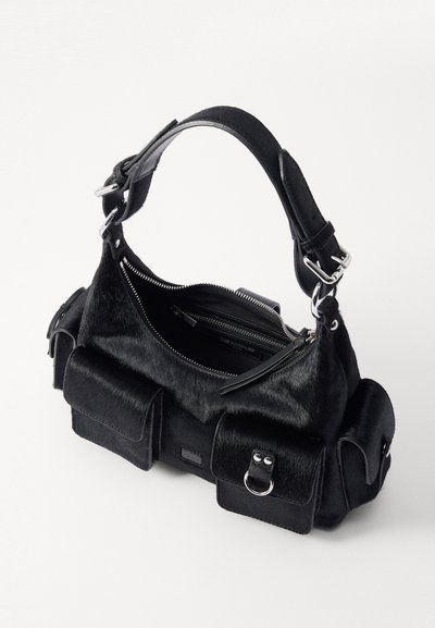 Sort håndtaske med et tekstureret pelslignende materiale, prydet med sølvhardware, dobbelt forlommer og et lynlåset hovedrum.