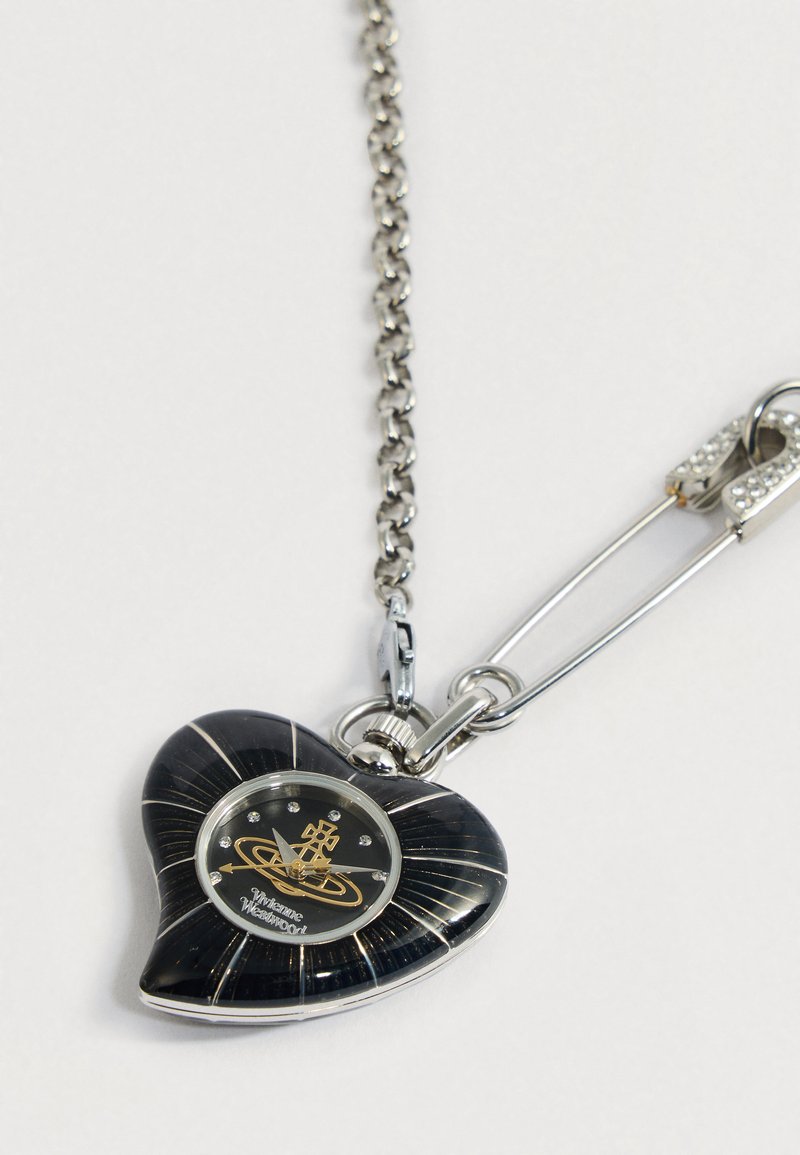 Hjärtaformat svart och silverfärgat fickur med kristalltimmarkörer på en kedja fäst vid en säkerhetsnål.