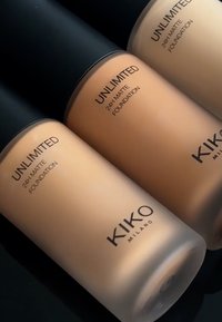 Tre KIKO Milano Unlimited 24H Matte Foundation-flasker i varierende beige toner; frostet glass med svarte lokk og trykte etiketter.