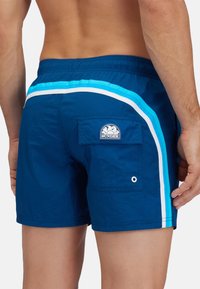 Marineblauwe zwemmershorts met lichtblauwe en witte zijstrepen. Heeft een achterzak en een logopatch op de achterkant. Verstelbare tailleband.