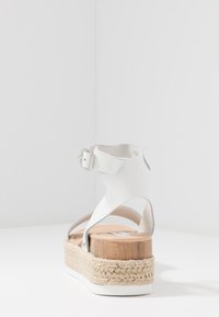 Sandale espadrille en cuir blanc avec une plateforme en bois, enroulement en jute, bride de cheville ajustable et texture lisse.