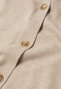 Beige Strickjacke mit glatter Textur und runden, hellbraunen Knöpfen entlang der Vorderleiste. Einfaches und minimalistisches Design.