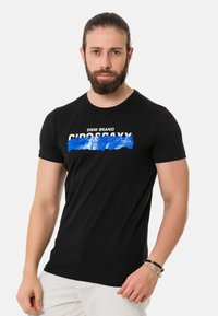 Schwarzes T-Shirt mit kurzen Ärmeln, das über die Brust mit weißem und blauem Grafiktext versehen ist. Es besteht aus weichem Stoff und hat einen Rundhalsausschnitt.
