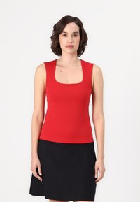 Top ajustado rojo con escote cuadrado, hecho de material elástico. Se lleva con una falda negra. Textura suave, sin patrones visibles.
