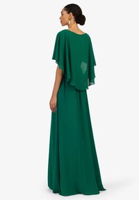 Langes grünes Kleid aus leichtem Stoff, mit fließenden Cape-Ärmeln und einem schlichten Rundhalsausschnitt, in lockerer Passform und in voller Länge.