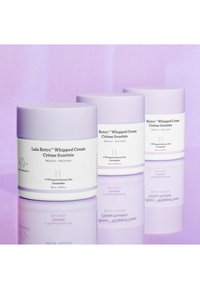 Drei weiße Gläser mit Lala Retro™ Whipped Cream und lavendelfarbenen Deckeln, die Text auf der Vorderseite und eine glatte, glänzende Oberfläche aufweisen.