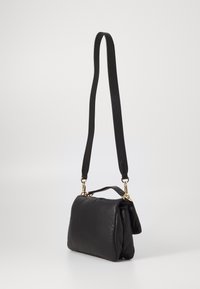 Borsa a mano in pelle nera con forma strutturata, dotata di una lunga tracolla regolabile e hardware in tonalità oro. Texture liscia, design minimale.
